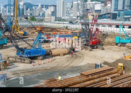 Grande cantiere urbano a Busan, Corea del Sud, con gru, escavatori, camion e lavoratori che costruiscono nuove infrastrutture cittadine. Immobili Foto Stock