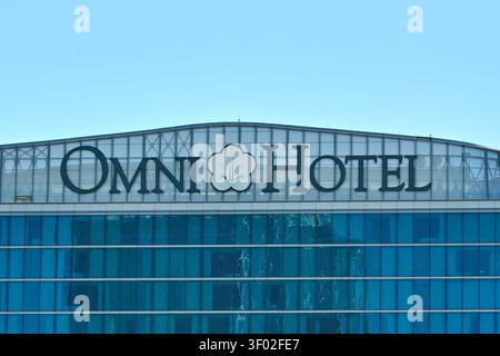 DALLAS, TX, USA - 16 FEBBRAIO 2024: Il logo dell'Omni Hotel è ben visibile sulla sommità di un moderno edificio in vetro. Il logo presenta un'audace blac Foto Stock