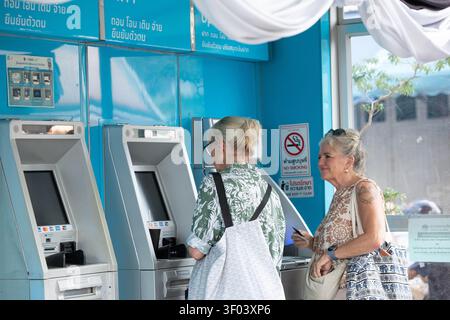 BANGKOK, TAILANDIA - 3 giugno 2026: Donne anziane che utilizzano ATM, profilo laterale Foto Stock