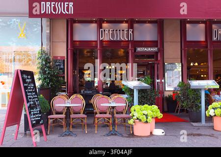 Berlino, Germania: Elegante area salotto all'aperto in stile parigino del ristorante Dressler, con sedie in vimini rosso, tavoli e un cartello con menù a lavagna Foto Stock