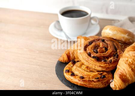 Pasticceria fresca e caffè serviti a colazione su un tavolo di legno. Foto Stock