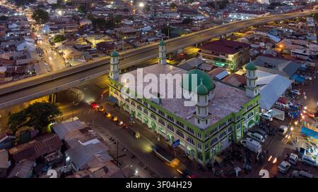 Vista aerea della Moschea centrale di Tamale con la sua cupola verde e i minareti illuminati di notte, situata vicino a un'autostrada sopraelevata a Tamale, nella regione settentrionale Foto Stock