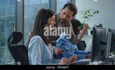 Tre operatori di diversità che lavorano nel call center, un CEO arrabbiato, controllano il lavoro aziendale insoddisfatto, parlano con una donna triste. Gruppo multietnico Foto Stock