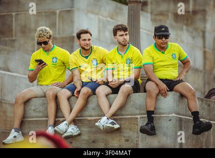 Quattro tifosi di calcio maschili in maglie brasiliane seduti insieme Foto Stock