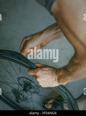 Primo piano di un uomo che fissa uno pneumatico per bicicletta Foto Stock