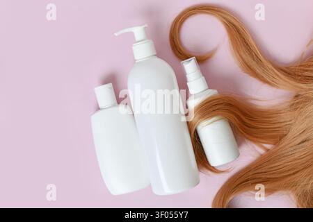 Filamenti e shampoo per la cura dei capelli, balsamo e bottiglie di olio per capelli su sfondo rosa chiaro Foto Stock
