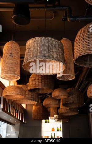 Lampade a sospensione in rattan intrecciato caldo in un interno accogliente di ristorante Foto Stock