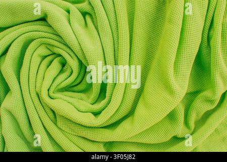 Primo piano orizzontale di una vivace t-shirt polo verde lime in tessuto mesh intrecciato in un bellissimo motivo a spirale con ombre morbide sul Foto Stock
