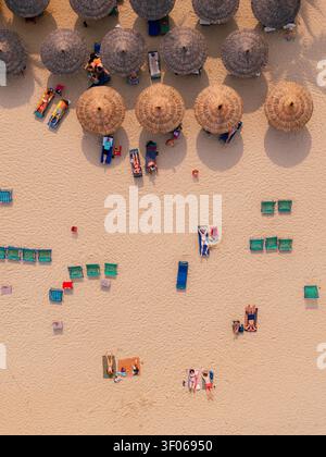 Vista aerea di una spiaggia sabbiosa con numerosi ombrelloni di paglia e lettini occupati da persone che si rilassano sotto il sole in Vietnam. Foto Stock