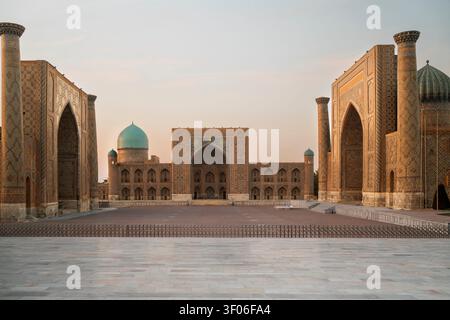Ampia vista di Piazza Registan a Samarcanda, Uzbekistan, con madrasa ornate, facciate piastrellate, archi e cupole al tramonto, che mostrano l'iconica via della Seta I. Foto Stock