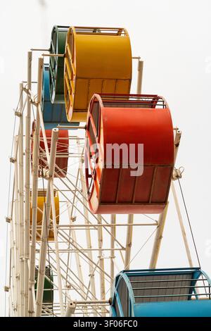 Vista ravvicinata delle colorate gondole della ruota panoramica su una struttura della ruota panoramica, mostrando cabine rosse, gialle e blu contro un cielo luminoso di giorno Foto Stock