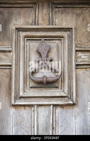 Porta in ghisa arrugginita e intemprata bussa su una vecchia porta di legno nella città vecchia di Roscoff, Finistere, Bretagna, Francia Foto Stock