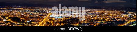 Un'ampia vista panoramica della città illuminata di Cuenca in Ecuador di notte, vista dal punto panoramico di Turi. Foto Stock