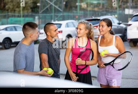 Giocatori di tennis uomini e donne che hanno conversazione sul parcheggio Foto Stock