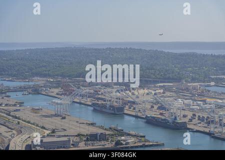 Stato di Washington, Stati Uniti, 20 giugno 2026 - grandi navi da carico attraccate in un porto trafficato con gru e container impilati sotto un cielo nebbioso. Foto Stock