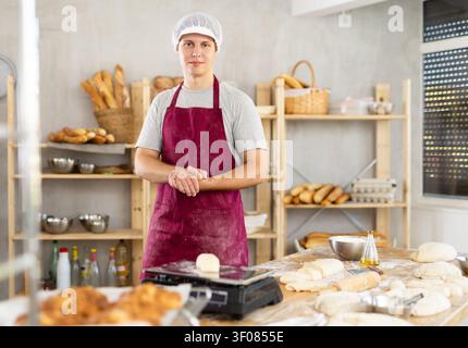 Ritratto di un giovane fornaio sorridente in uniforme in panetteria Foto Stock