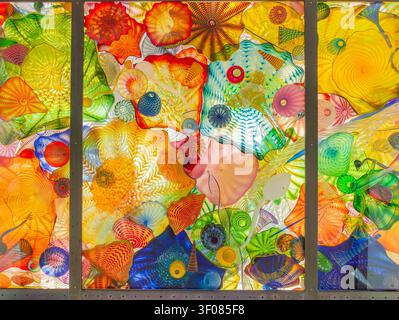 Washington State, JUN 25, 2026 - Una vibrante installazione artistica in vetro con pannelli traslucidi con motivi vorticosi e forme organiche in un luminoso colle Foto Stock