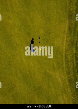 Veduta aerea di un golfista che mette su un green con un flagstick e una lunga ombra gettata sull'erba, Baden-Wurttemberg, Germania. Foto Stock
