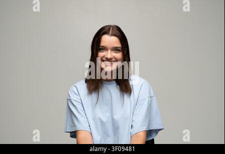 Giovane donna sorridente, che esprime gioia e sicurezza con un'espressione facciale positiva e una bellezza naturale in studio Foto Stock