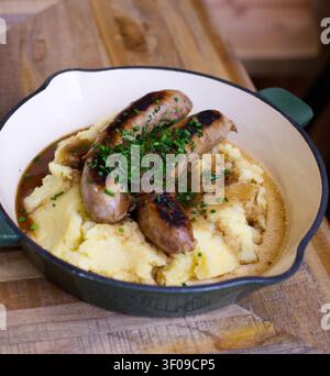 Salsicce grigliate servite con purè di patate cremoso in una teglia rustica Foto Stock