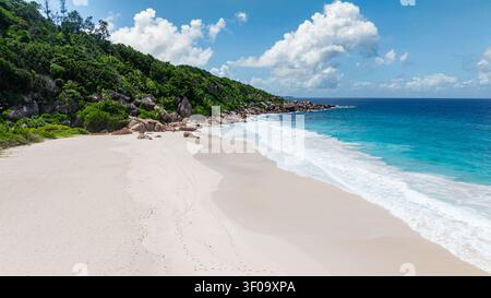 Bellissima spiaggia isolata con acque limpide e sabbia bianca, circondata da rocce. La Digue, Seychelles. Foto Stock