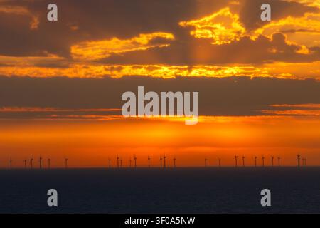Fila di turbine eoliche al tramonto lungo la costa inglese, Regno Unito, Europa a giugno Foto Stock