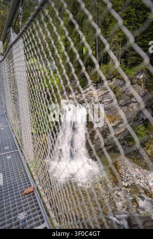 Prima di un reticolo di sicurezza lungo un ponte sospeso con vista su una cascata impetuosa, Austria Foto Stock