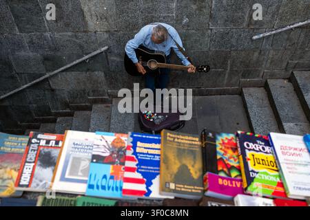 Tbilisi, Georgia. 7 luglio 2026. Un uomo suona la chitarra su gradini di pietra mentre i libri sono distribuiti in vendita a Tbilisi, Georgia, il 7 luglio 2026. (Foto di Moe Zoyari/Sipa USA) credito: SIPA USA/Alamy Live News Foto Stock