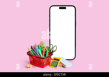 Smartphone con materiale scolastico su sfondo rosa Foto Stock