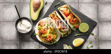 Tacos di gamberi con avocado e verdure fresche su tavola di ardesia Foto Stock