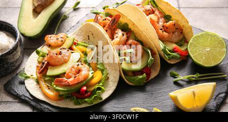 Tacos di gamberi con avocado e verdure su tavola Foto Stock