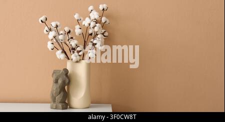 Steli di cotone in vaso con scultura astratta sul tavolo Foto Stock