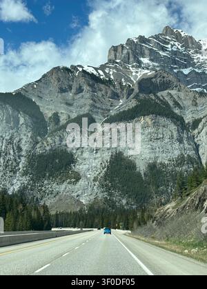 Picchi massicci si innalzano drammaticamente sopra l'autostrada che si snoda attraverso il Parco Nazionale di Banff, Alberta, Canada. Foto Stock