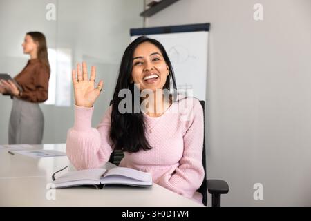 Donna d'affari indiana che saluta la telecamera e fa una videochiamata a un cliente Foto Stock
