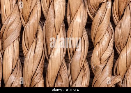 Primo piano di fibre naturali tessute strette che formano un motivo intrecciato. La texture dettagliata evidenzia i toni terrosi e la maestria artigianale, spesso visti in Foto Stock