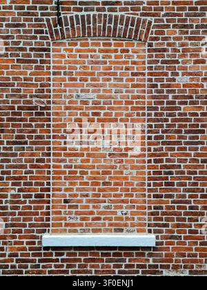 Vista frontale a formato completo dell'esterno di una finestra murata in un muro di mattoni. Foto Stock