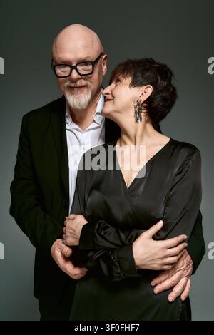Una coppia di anziani amorevoli condivide un momento gioioso e caloroso, vestiti elegantemente insieme. Foto Stock