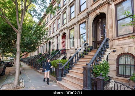 Giovane donna che passeggia intorno alle case storiche e ai vecchi edifici residenziali intorno al Hamilton Park a Jersey City, New Jersey, USA. Foto Stock