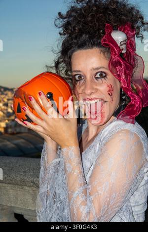Donna che posa in costume da vampiro di Halloween con zucca Foto Stock