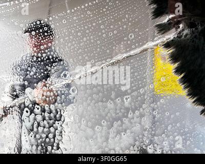 Prima di schiuma di sapone e bolle sul vetro durante un lavaggio professionale dell'auto. Concetto di manutenzione del veicolo e servizio di detailing. Foto Stock