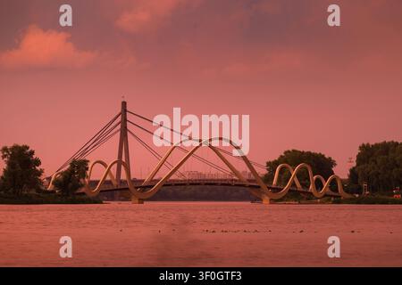 Luce dorata del tramonto dopo un potente temporale illumina il Wave Bridge e il North Bridge sul fiume Dnipro a Kyiv, Ucraina, creando una scena drammatica Foto Stock