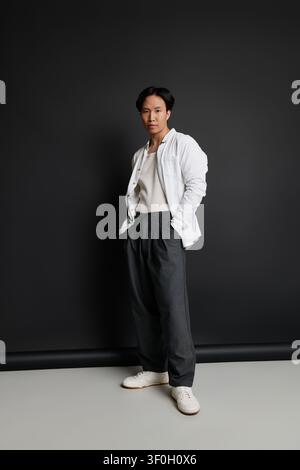 Giovane uomo sicuro di sé posa in abiti eleganti su uno sfondo scuro. Foto Stock