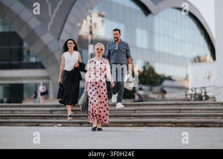 Donna elegante che guida gli amici lungo le scale della città in un contesto urbano moderno Foto Stock