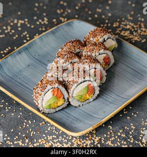 Un piatto di deliziose e splendidamente presentate sushi roll e sashimi disposte su un tavolo di legno. Foto Stock