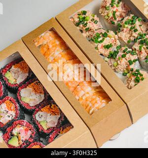 Una foto che mostra una varietà di tipi di sushi ordinatamente disposti e confezionati in una scatola. Foto Stock