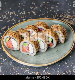 Un piatto pieno di una varietà di rotoli di sushi posizionati su un tavolo di legno. Foto Stock