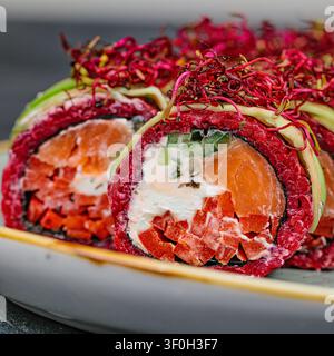 Un piatto colmo di un assortimento di rotoli di sushi adornati con varie guarnizioni, mostrati in una disposizione visivamente accattivante. Foto Stock