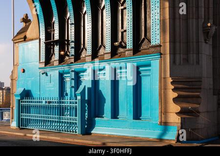 Un primo piano evidenzia i dettagli industriali del Tower Bridge a Londra. Pannelli metallici blu brillanti, travi verticali in acciaio scuro con rivetti e un o Foto Stock