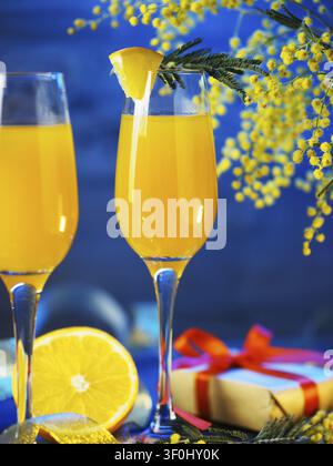Cocktail mimosa e fiori su uno sfondo blu Foto Stock
