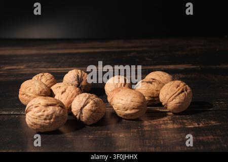 Prima vista di noci intere con gusci strutturati su un tavolo di legno rustico Foto Stock